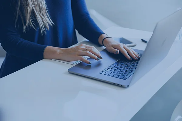 Frau in blauem Blazer am Laptop, die sinnbildlich für das Business Strategie Angebot von Ottosen Studio steht